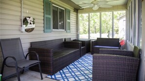 A covered porch with wicker furniture, a ceiling fan, and a welcome sign. - Cozy 3-Bedroom Beach Cottage (Turkey Point)