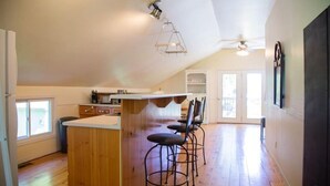 A spacious kitchen with a wooden island, bar stools, and a ceiling fan. - Cozy 3-Bedroom Beach Cottage (Turkey Point)