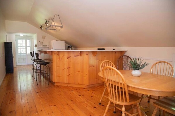 A kitchen with wooden cabinets, a dining table with chairs, and a small island.