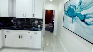 Een moderne keuken met witte kasten, een zwart aanrecht en een marmeren vloer.