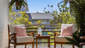 Un balcon avec deux chaises en bois, une petite table et une plante suspendue.