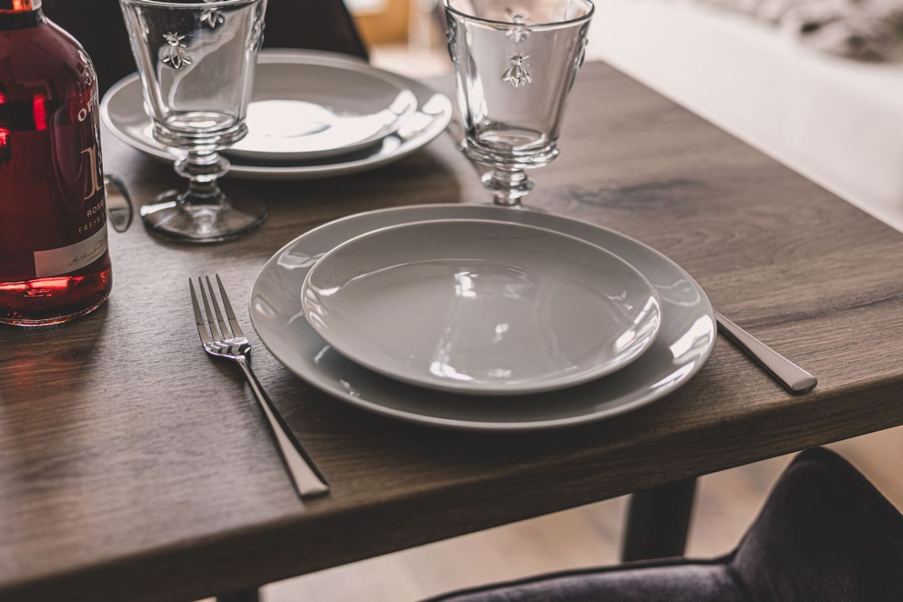 Una mesa de comedor dispuesta con un plato, un tenedor, un cuchillo y una copa.