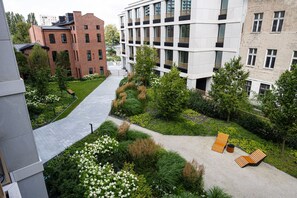 Un cortile con un vialetto, zone relax e vegetazione rigogliosa.