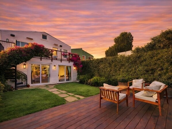 Une maison moderne dotée d’une terrasse, d’un espace salon extérieur et d’un jardin bien entretenu.