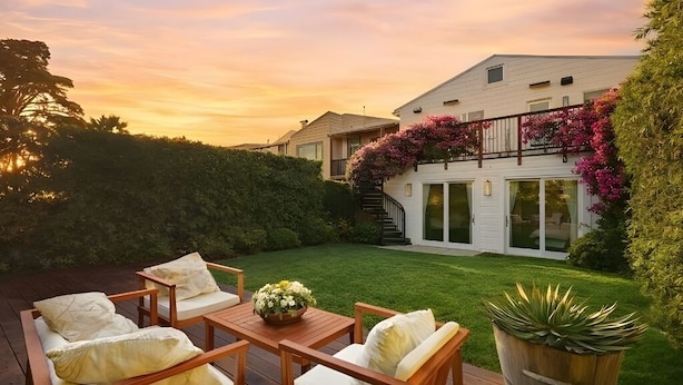 A patio with wooden furniture and a potted plant.