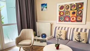 A modern living room with a sofa, armchair, and round table. - Lovely apartment for 4 people with WIFI, TV and balcony (Wolgast)
