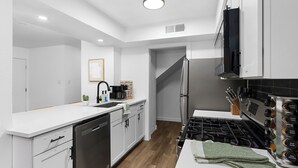 A modern kitchen with white cabinetry, a stainless steel refrigerator, a gas stove, and a dishwasher. - Prime Location Zilker Park & SoCo Chic (Austin)