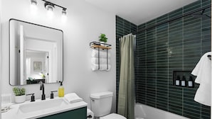 A modern bathroom with a white sink, black faucet, green cabinet, white toilet, and a shower with green tiles. - Prime Location Zilker Park & SoCo Chic (Austin)