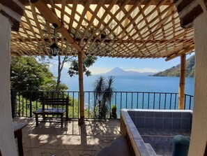 A covered outdoor area with a bench, a view of a body of water, and a mountain in the distance. - Casita With View Of Lake Atitlan (Panajachel)