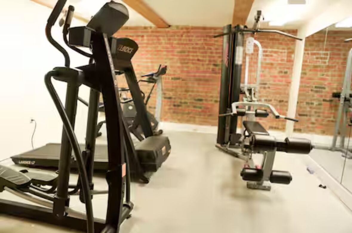 Une salle de sport équipée de matériel d’exercice, notamment un tapis de course et des appareils de musculation.