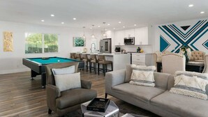 A modern living room with a pool table, sofas, and a kitchen in the background. - Sunkiss - Pool, Spa & Mini Golf - Mins to Old Town (Scottsdale)