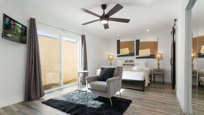 A modern hotel room with a large bed, a seating area with a chair, a ceiling fan, and a TV mounted on the wall. - Sunkiss - Pool, Spa & Mini Golf - Mins to Old Town (Scottsdale)