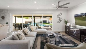 A living room with a sofa, coffee table, TV, and a fireplace. - Sunkiss - Pool, Spa & Mini Golf - Mins to Old Town (Scottsdale)