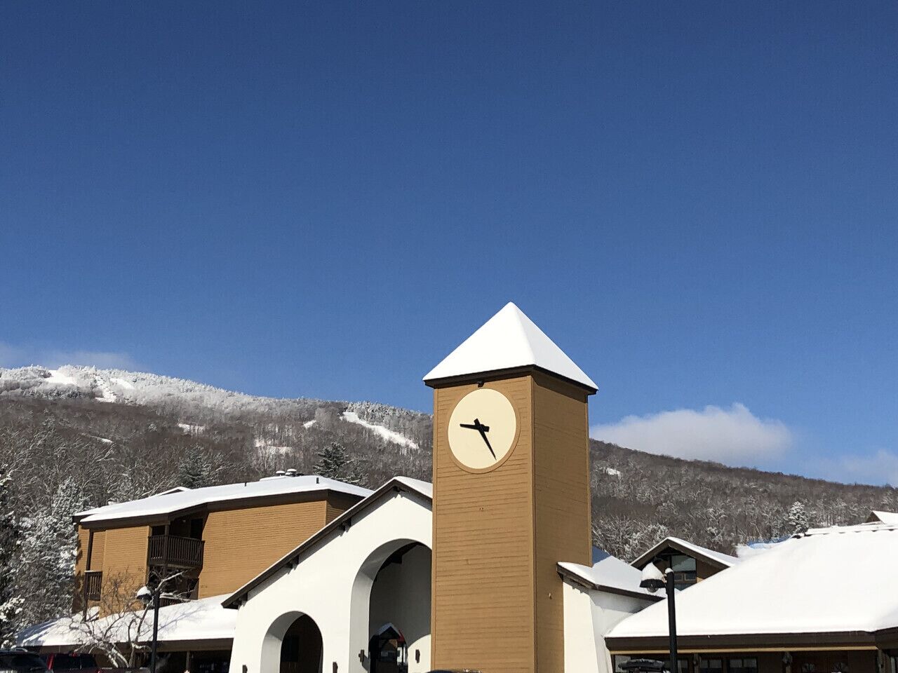A building with a clock tower, arched windows, and a snowy mountain backdrop.