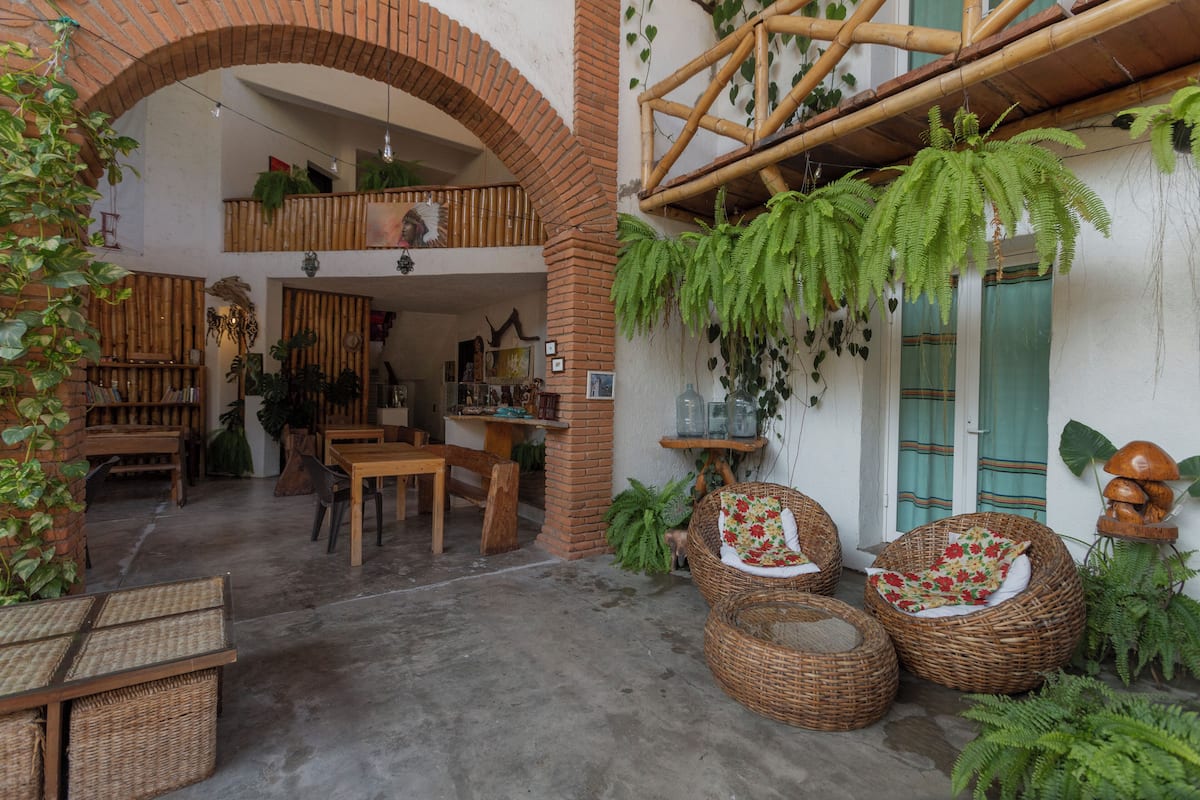 A spacious indoor area with a brick archway, wicker furniture, and hanging ferns.