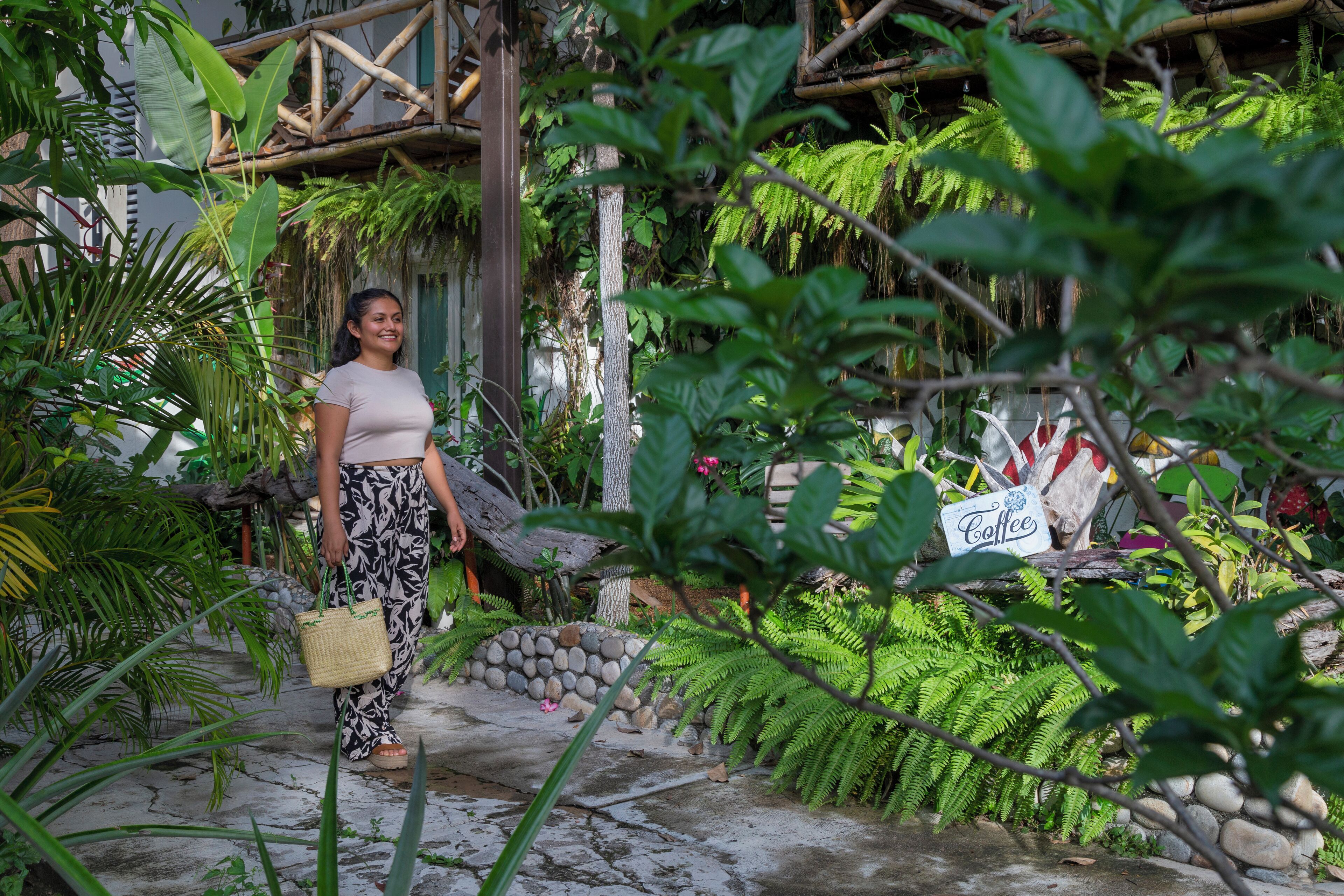 Una mujer camina por un jardín con un letrero que dice 'Coffee'.