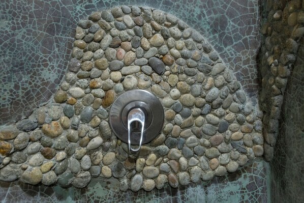 Ducha con diseño de mosaico circular y grifo metálico.