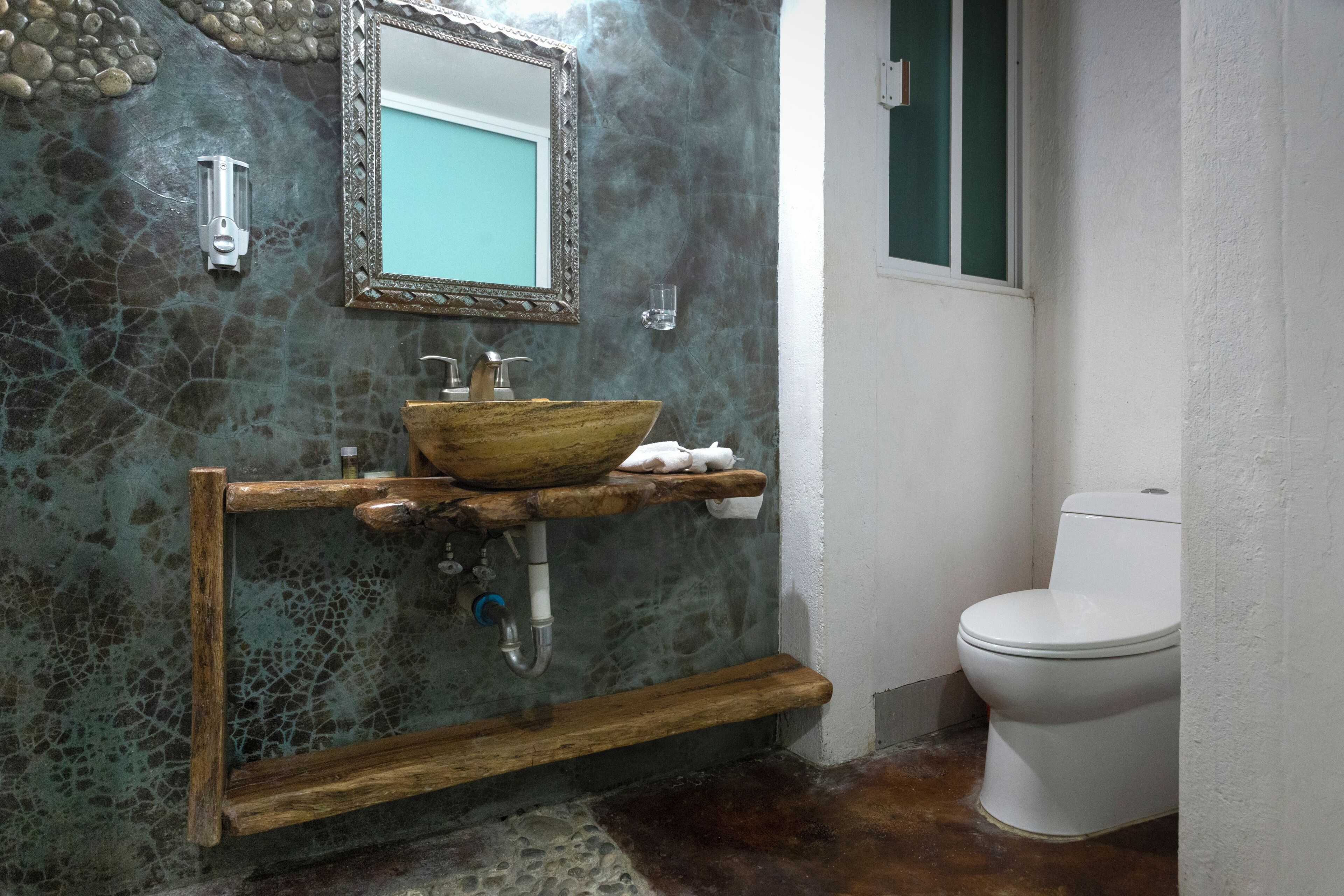 A bathroom with a stone backsplash, wooden vanity, and a white toilet.