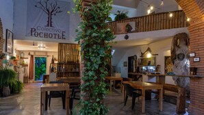 Un ambiente accogliente con mobili in legno, una pianta grande e un cartello con scritto "Collectivo Pochotle".
