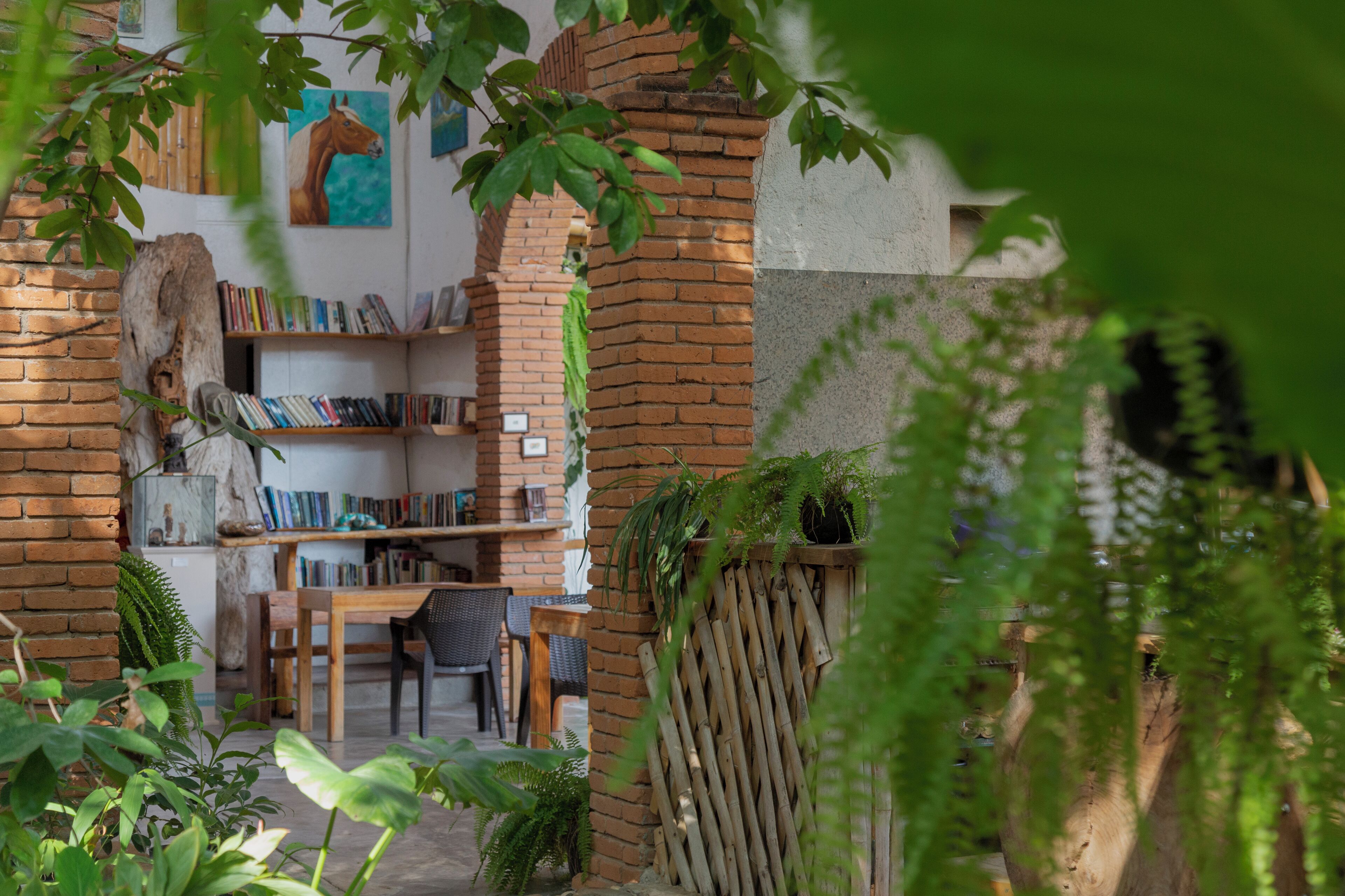 A cozy reading nook with a brick wall, bookshelves, and a wooden table.