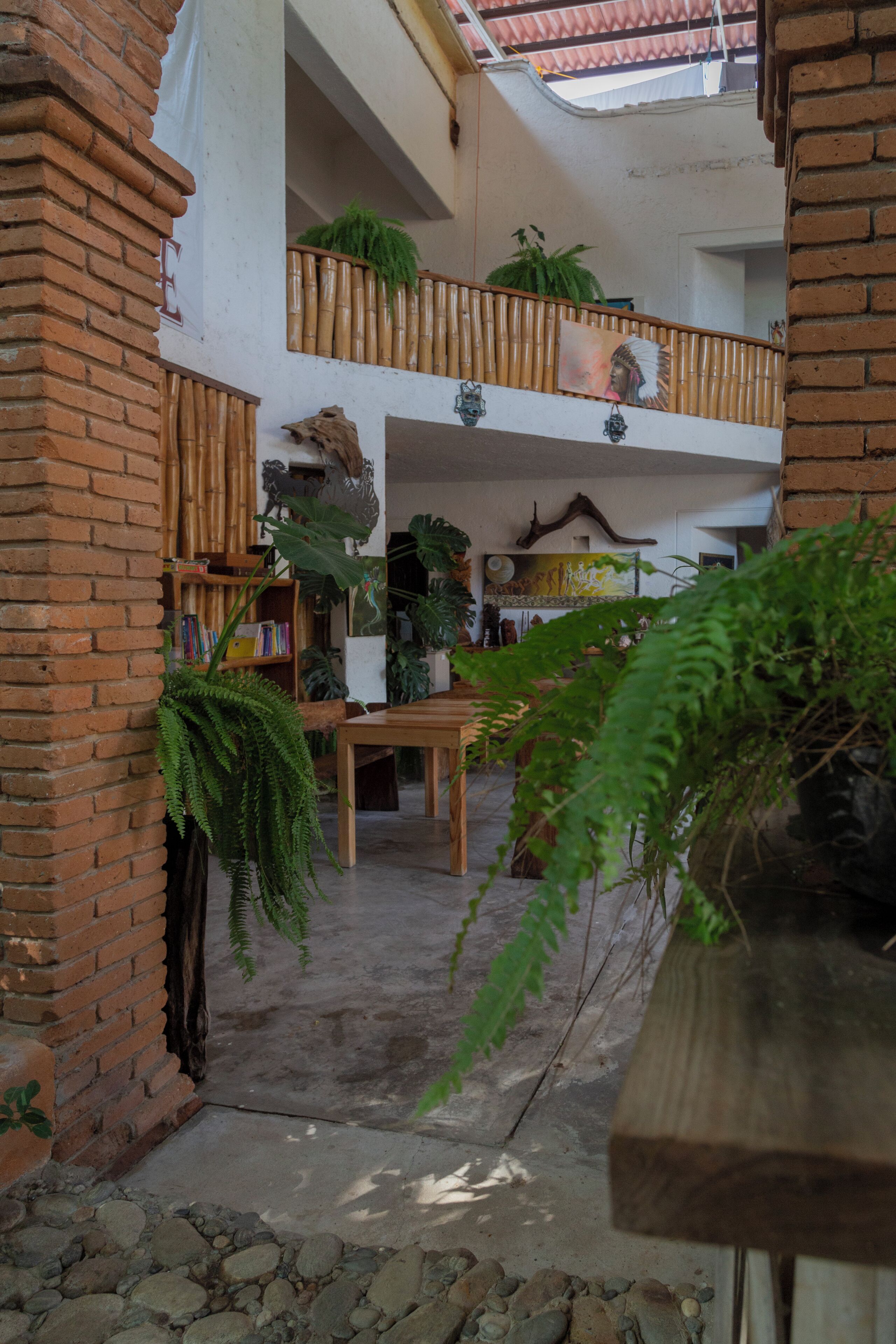 Un vaste atrium doté d’une table et de chaises en bois, entouré de plantes en pot et d’une rambarde en bambou.