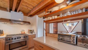A kitchen with a stove, oven, and a toaster. There are wooden cabinets and a countertop.