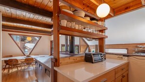 A kitchen with wooden cabinets, a countertop, and a built-in shelf with dishes and glasses.