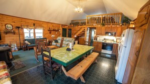 A cozy cabin interior with a wooden dining table, benches, a sofa, and a kitchen area. - Secluded Woodland Retreat Surrounded by Forest Views & Wildlife (Mill Hall)