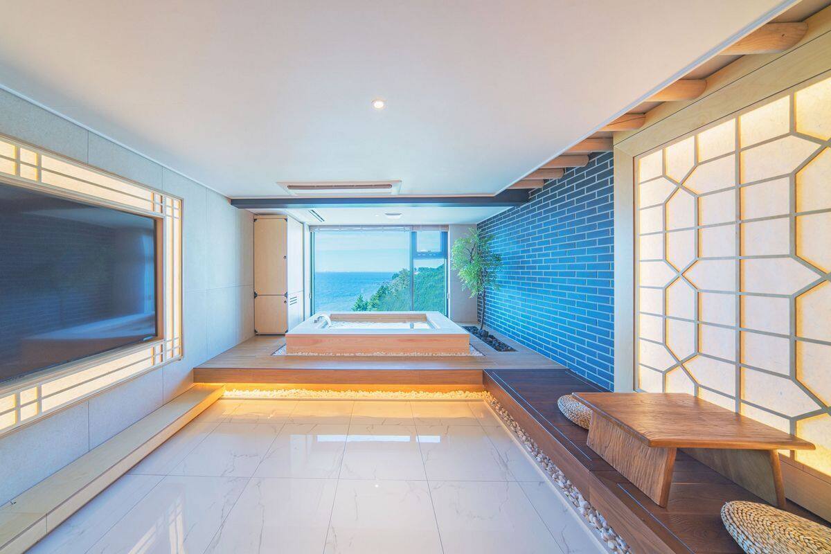 Un interior moderno con un televisor grande, un área de estar con vistas y una pared de ladrillo con un diseño luminoso geométrico.