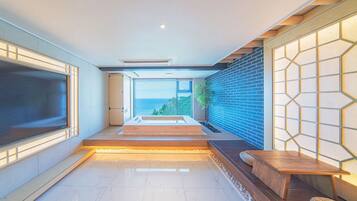 A modern interior with a large TV, a seating area with a view, and a brick wall with a geometric light pattern.