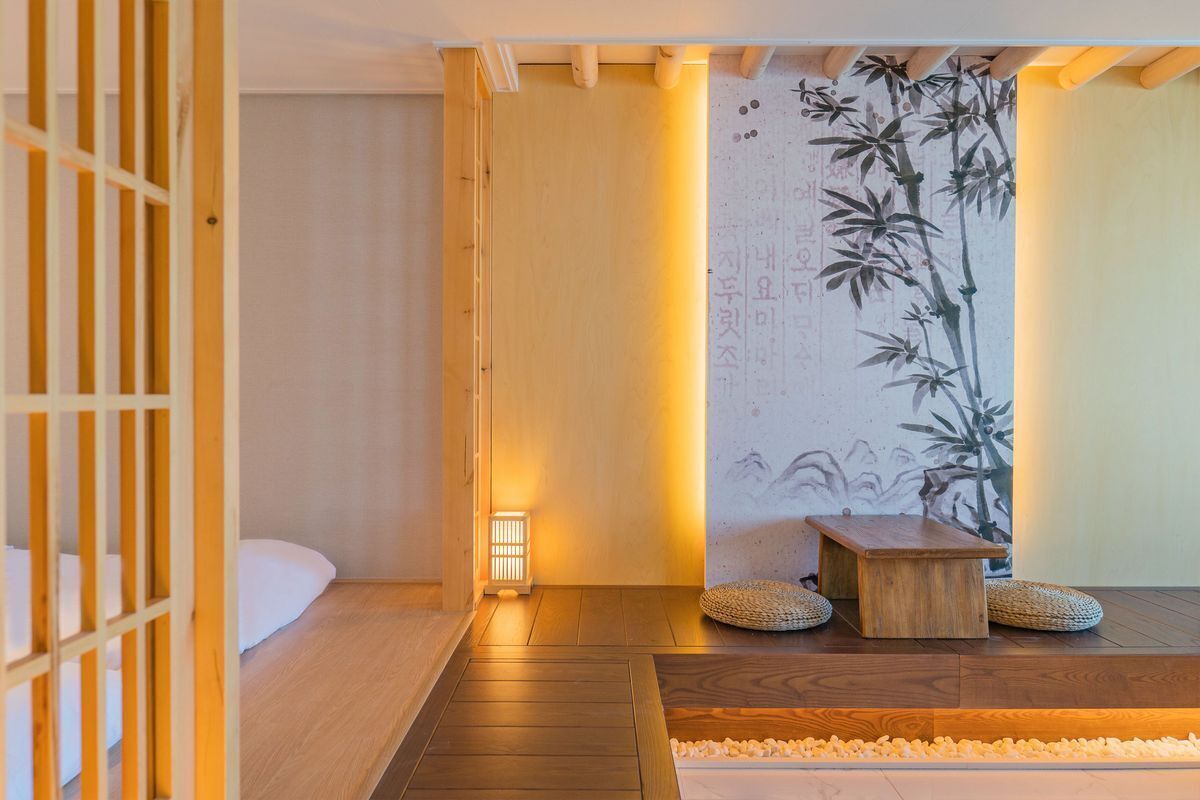 A traditional Japanese room with tatami flooring, a shoji screen, a low wooden table, and a wall with calligraphy.