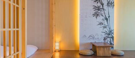 A traditional Japanese room with tatami flooring, a shoji screen, a low wooden table, and a wall with calligraphy.