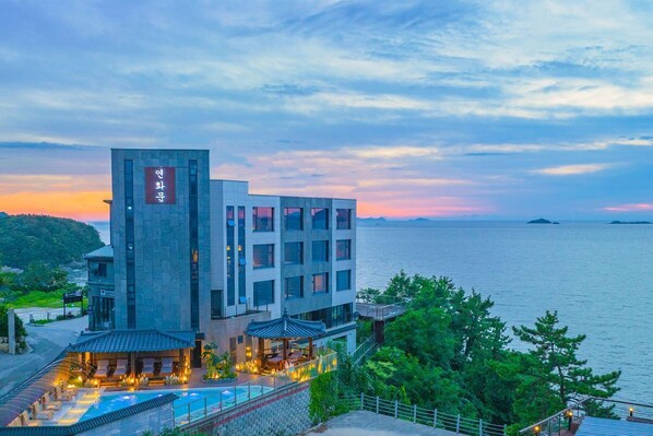 Un hôtel moderne doté d’une piscine et d’un espace extérieur aménagé, offrant une vue sur un plan d’eau.