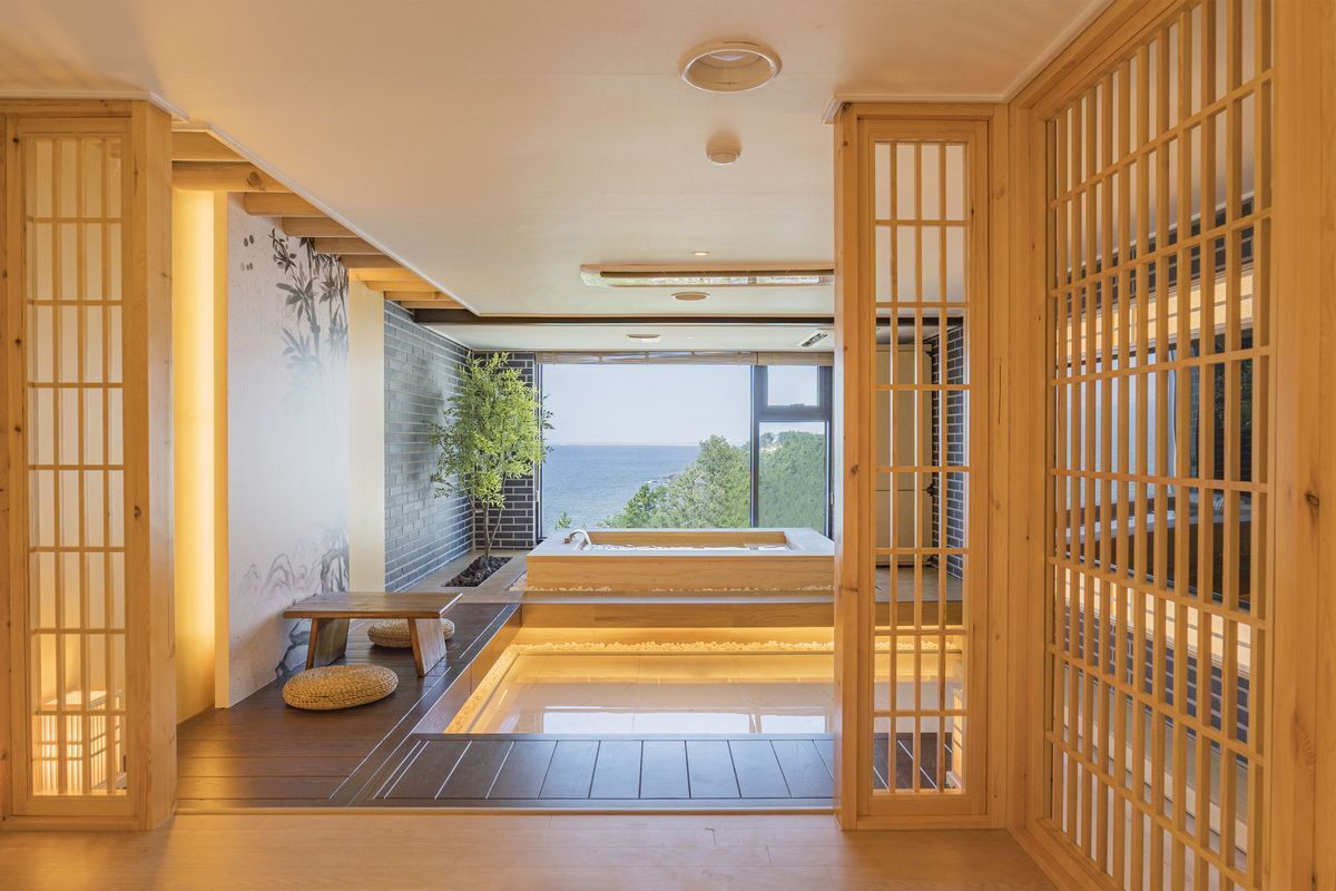 Un intérieur moderne avec vue sur la mer, un plancher en bois, un coin salon et une grande fenêtre.