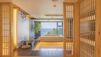 Un intérieur moderne avec vue sur la mer, un plancher en bois, un coin salon et une grande fenêtre.