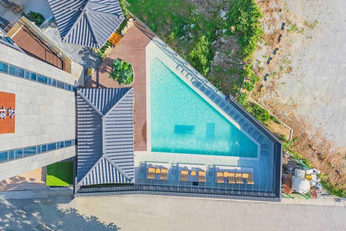 An aerial view of a hotel with a large swimming pool, a covered outdoor area, and a building with a sign.
