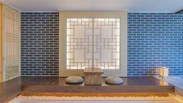 A traditional Japanese-style room with a wooden floor, a low wooden table, and two cushions.