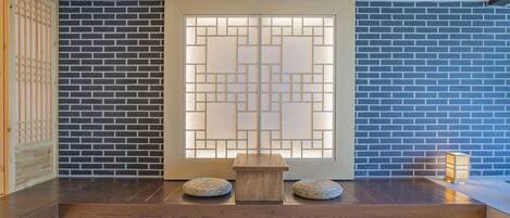 Una habitación tradicional japonesa con suelo de madera, una mesa baja de madera y dos cojines.