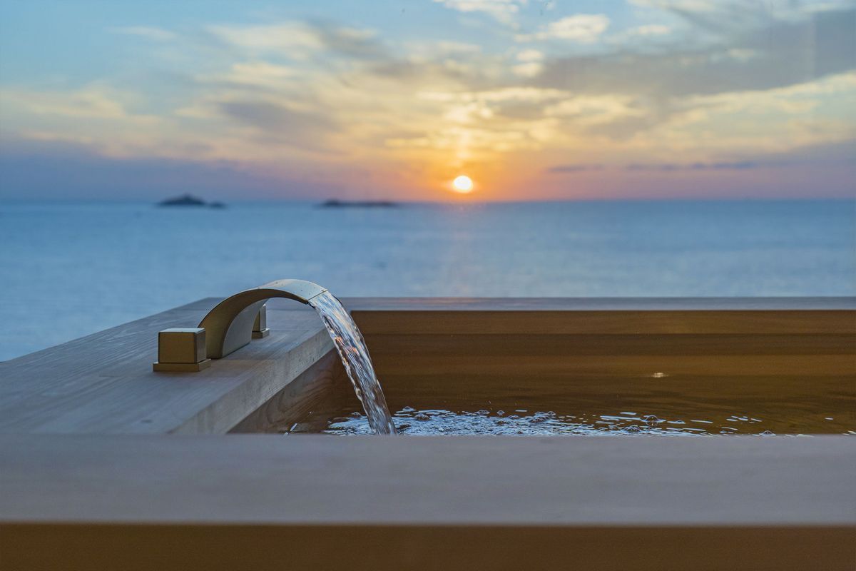 A sunset over the ocean with a water feature in the foreground.