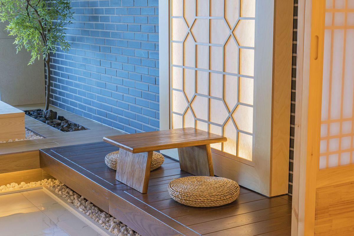 A wooden bench with woven cushions, a small table, and a traditional Japanese sliding door with a geometric pattern.