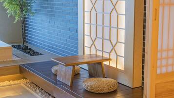 A wooden bench with woven cushions, a small table, and a traditional Japanese sliding door with a geometric pattern.
