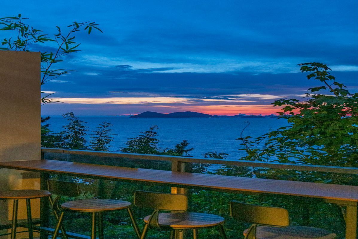 A balcony with a view of the sea at sunset.