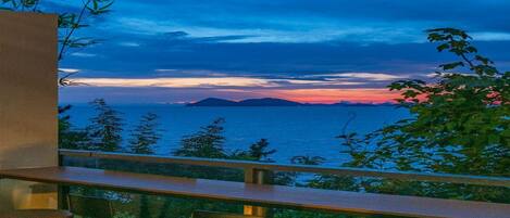 A balcony with a view of the sea at sunset.