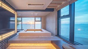 Un spa moderno con una bañera grande, vistas al mar y un amplio ventanal.
