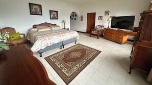 Ein Schlafzimmer mit einem Bett, einem Schminktisch, einem Fernseher und einem Sessel.