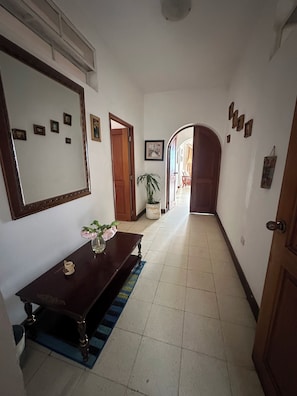 A hallway with a wooden bench, a potted plant, and framed pictures on the walls.