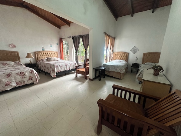 A bedroom with two beds, a wooden chair, a small table, and a nightstand.