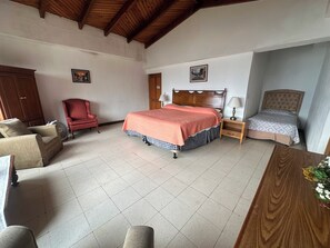 A bedroom with a large bed, a chair, a wooden cabinet, and a small table with a lamp. - Large House With View To Lake Atitlan (Panajachel)