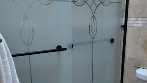 Ein Badezimmer mit Duschkabine aus Glas, Toilette und Handtuchhalter.
