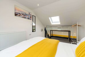 Ein Schlafzimmer mit Bett, Dachfenster, einem Gemälde und einer Heizung.
